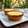 A small, bright yellow lemon-shaped dessert with a glossy finish, styled to look like a realistic lemon, placed on a clean plate.