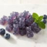 Homemade blueberry jelly gummies in bear and heart shapes with fresh blueberries
